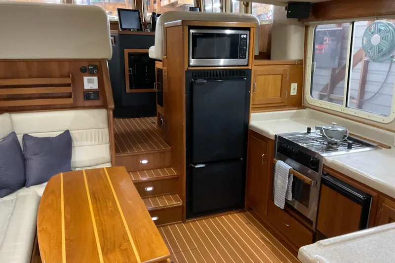 Hot Tuna Yacht Photos Pics Interior of 2002 American Tug Hull #24, featuring kitchen and seating area with wood accents.