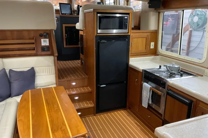 Hot Tuna Yacht Photos Pics Cozy 2002 American Tug interior with kitchen, dining area, and wooden finishes.