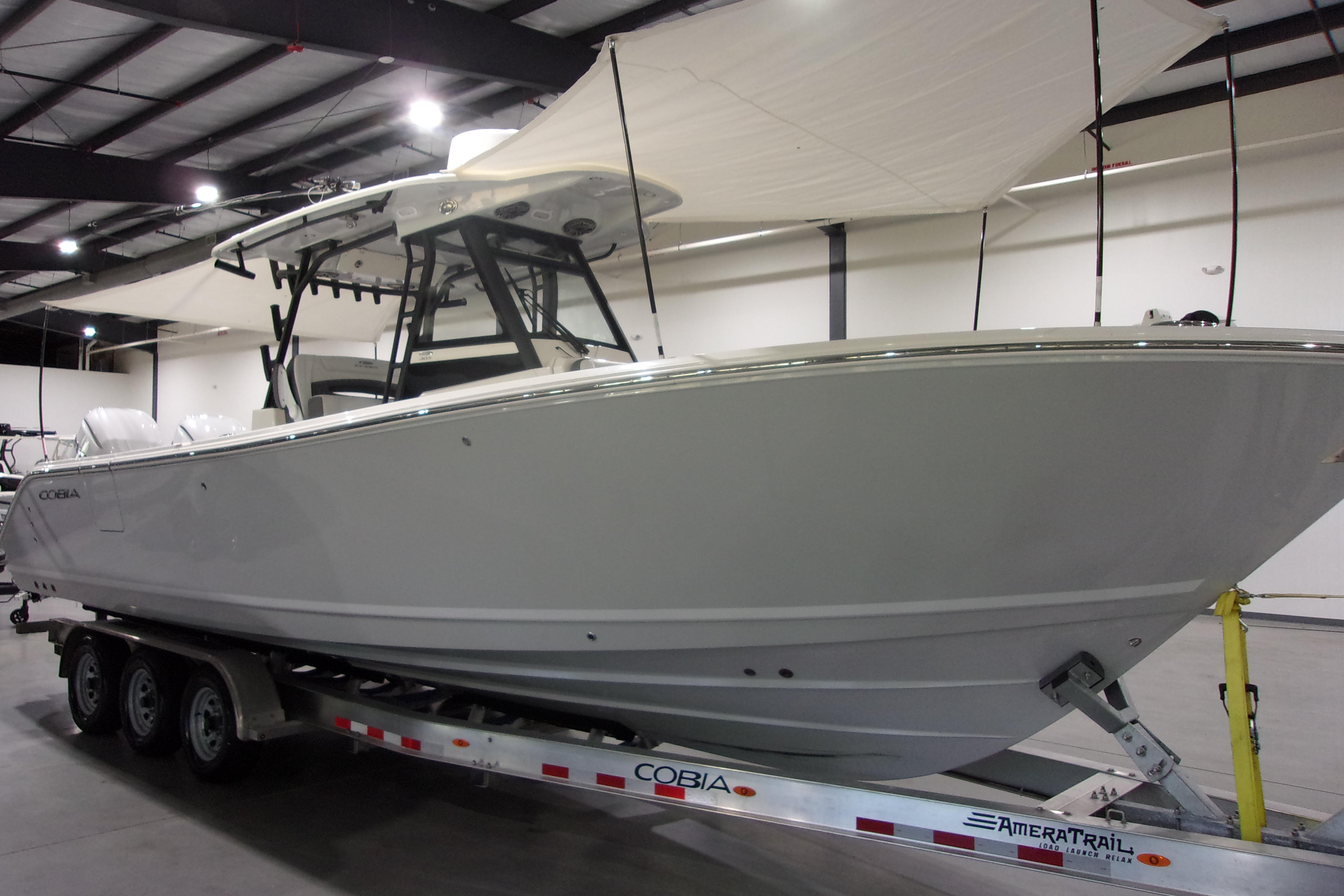 2026 Cobia 305 Center Console boat on trailer in indoor showroom.