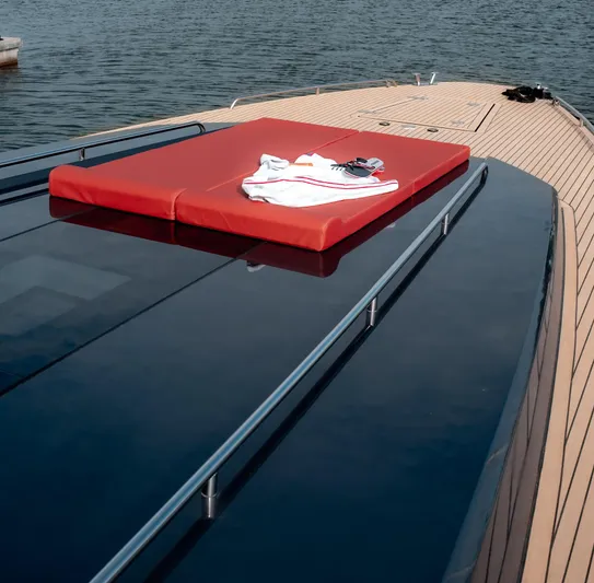 Explorer 1 Yacht Photos Pics 2024 Ridas 62 yacht deck with red sunbed and clothing, on calm water.