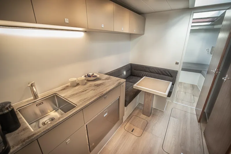 Explorer 1 Yacht Photos Pics Modern kitchen and dining area in 2024 Ridas 62 yacht, featuring sleek cabinetry and compact design.