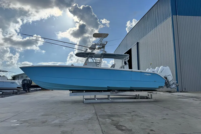  Yacht Photos Pics 2020 Invincible 40 Catamaran in blue, docked outside a large warehouse under a cloudy sky.
