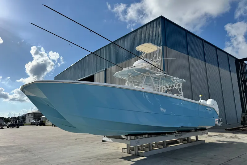  Yacht Photos Pics 2020 Invincible 40 Catamaran in light blue, docked near a large warehouse under a sunny sky.