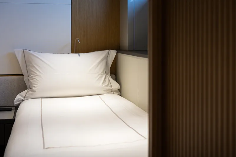 Mini K2 Yacht Photos Pics Modern yacht cabin with a neatly made bed, featuring wooden accents and soft lighting.