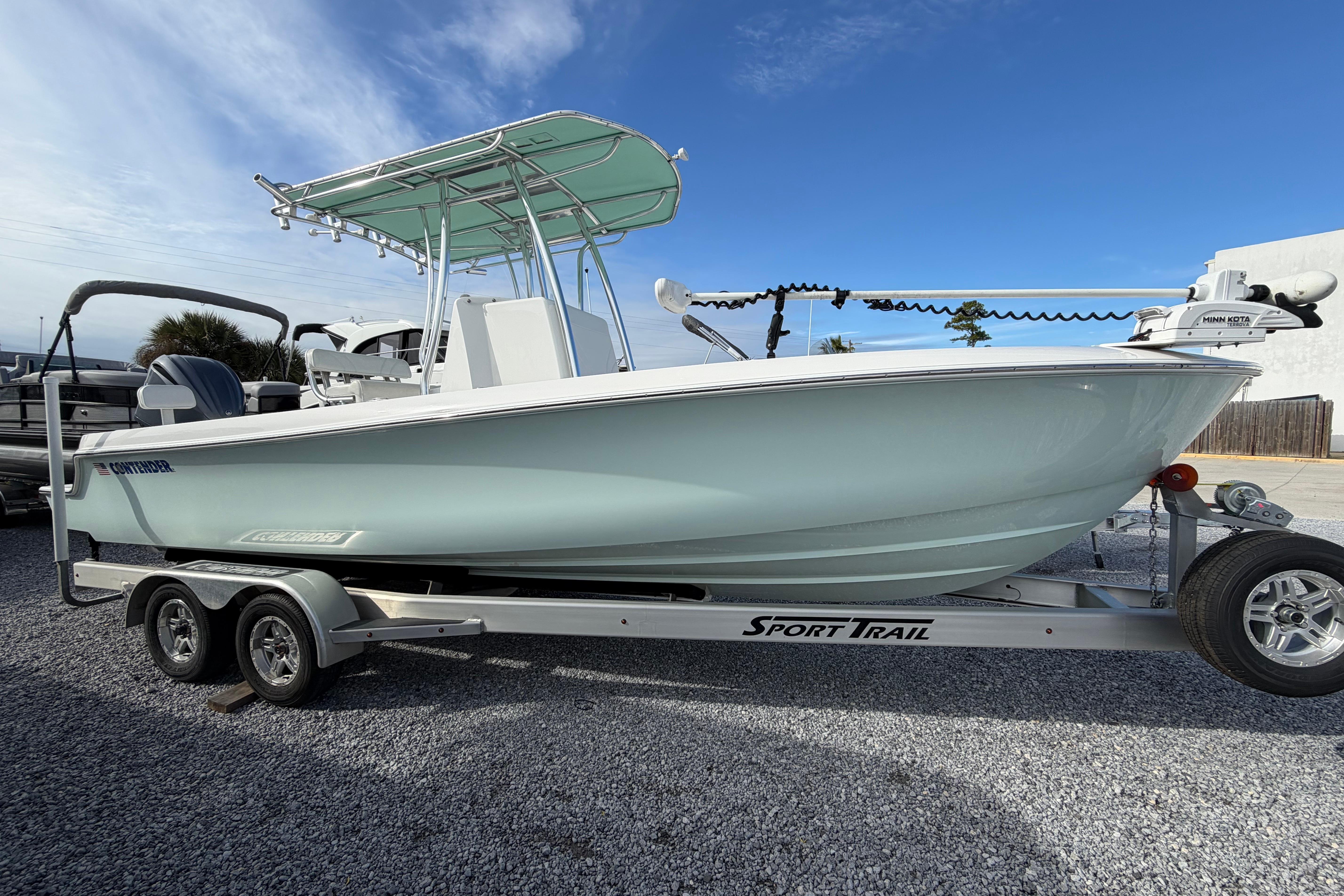 2023 Contender 24 Sport boat on trailer, parked outdoors under clear blue sky.