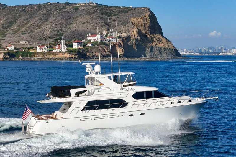 Encore Yacht Photos Pics 2006 Ocean Alexander 64 Pilothouse yacht cruising near rocky coastline and lighthouse.