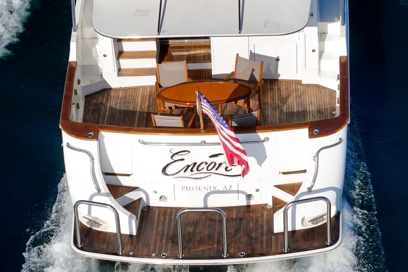 Encore Yacht Photos Pics Rear view of 2006 Ocean Alexander 64 Pilothouse yacht with American flag and deck seating.
