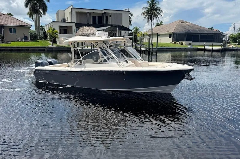  Yacht Photos Pics 2020 Grady-White Freedom 285 boat on a calm waterfront, with modern homes in the background.