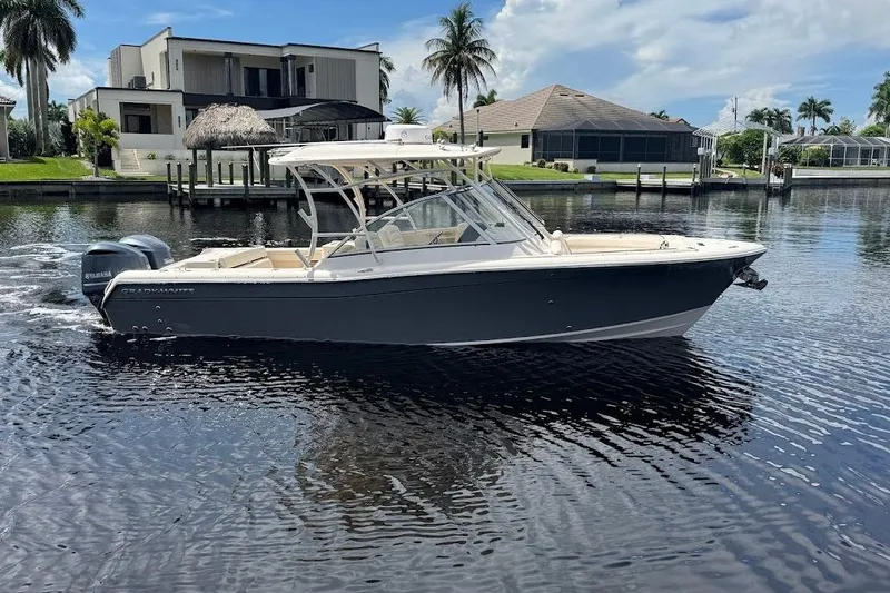  Yacht Photos Pics 2020 Grady-White Freedom 285 boat on a calm waterfront, with modern homes in the background.