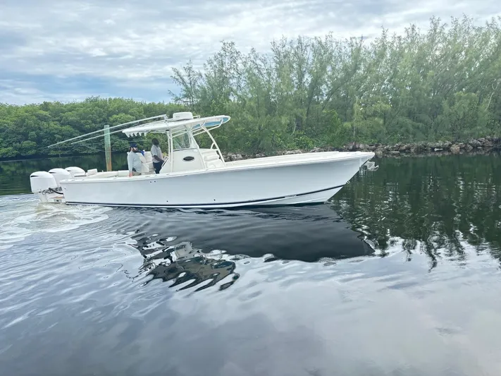  Yacht Photos Pics 2015 Regulator 34 CC boat cruising on calm water near lush greenery.