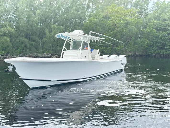  Yacht Photos Pics 2015 Regulator 34 CC boat on calm water, surrounded by lush greenery.