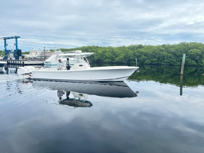  Yacht Photos Pics 2015 Regulator 34 CC boat on calm water near a marina, with lush greenery in the background.