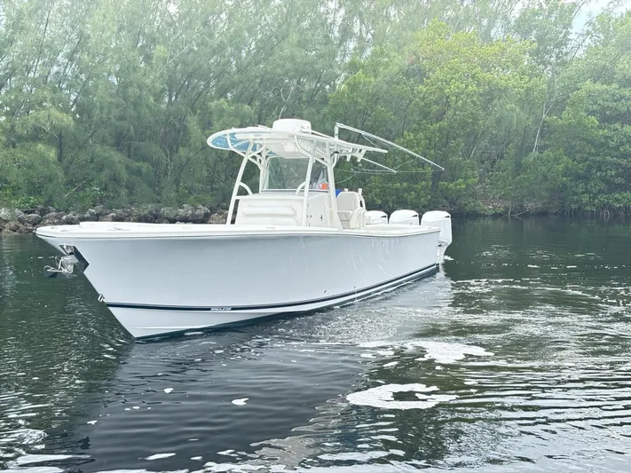  Yacht Photos Pics 2015 Regulator 34 CC boat cruising on calm water near lush greenery.
