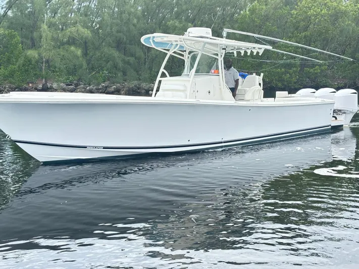  Yacht Photos Pics 2015 Regulator 34 CC boat on calm water, surrounded by lush greenery.