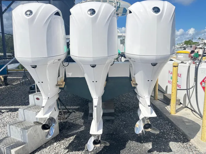  Yacht Photos Pics Triple outboard engines on a 2015 Regulator 34 CC boat, docked on gravel.