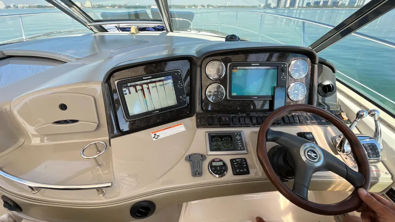 Lowest Price In Usa Yacht Photos Pics 2008 Sea Ray 44 Sundancer helm with navigation screens and steering wheel, overlooking calm waters.