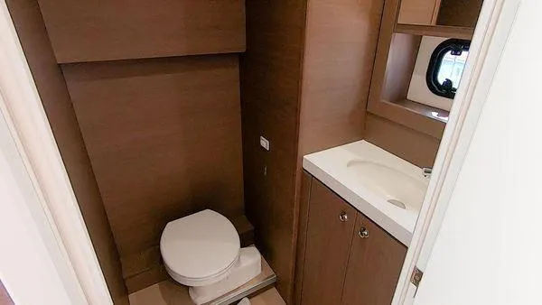 Joy Yacht Photos Pics Modern yacht bathroom with wooden cabinetry, toilet, and sink. Bali 5.4, 2021 model.