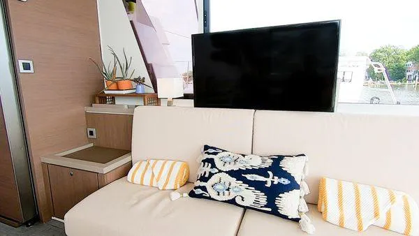 Joy Yacht Photos Pics Modern yacht interior with beige sofa, decorative pillows, and a flat-screen TV. Bali 5.4, 2021 model.