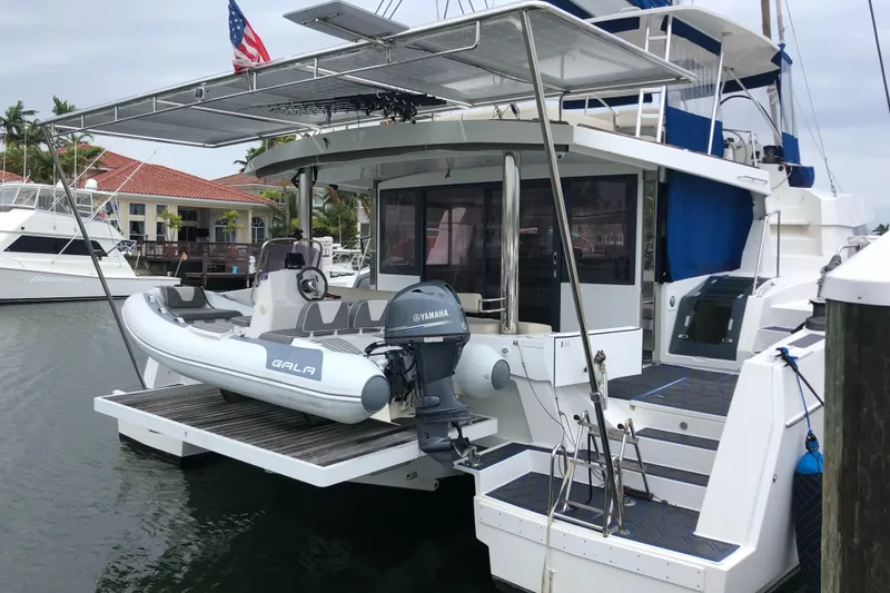 Joy Yacht Photos Pics Bali 5.4 catamaran docked with inflatable boat, 2021 model, marina setting.