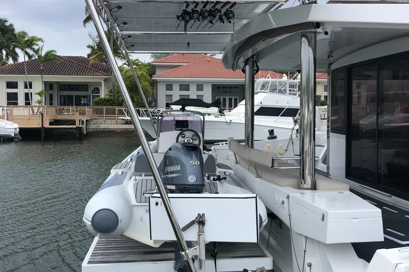 Joy Yacht Photos Pics Bali 5.4 yacht docked, featuring Yamaha motor, modern design, and waterfront homes in the background.
