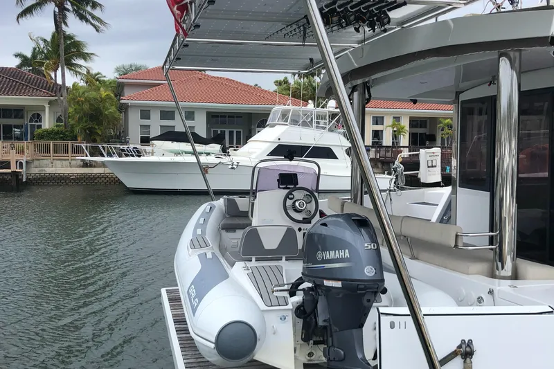 Joy Yacht Photos Pics Bali 5.4 catamaran docked near waterfront homes, featuring a Yamaha outboard motor.
