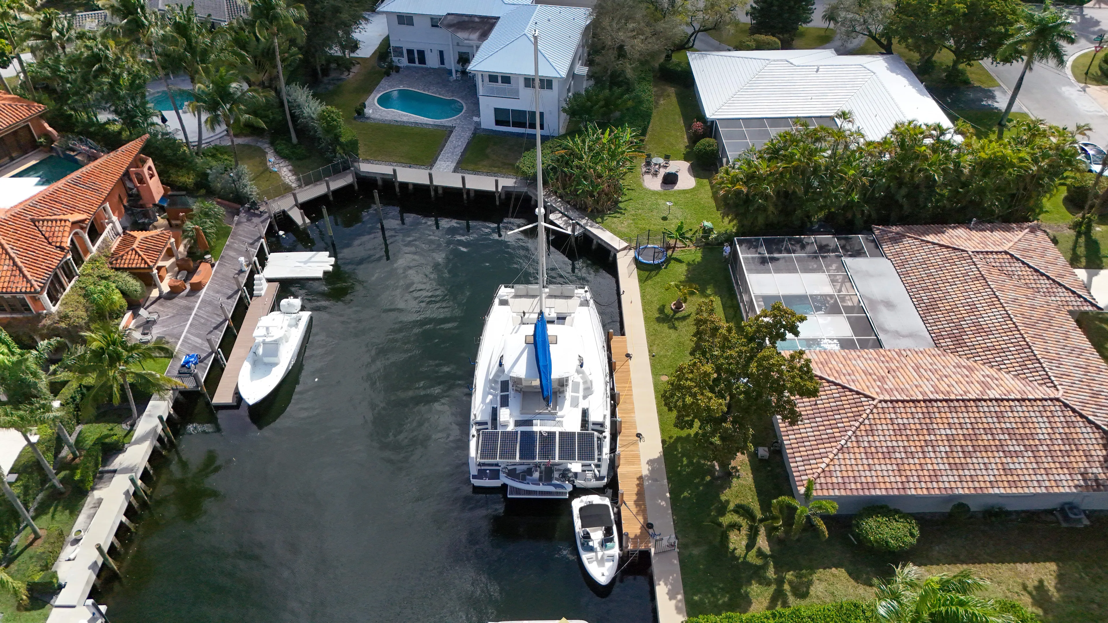 Joy Yacht Photos Pics Aerial view of a Bali 5.4 catamaran docked in a residential canal, surrounded by houses.