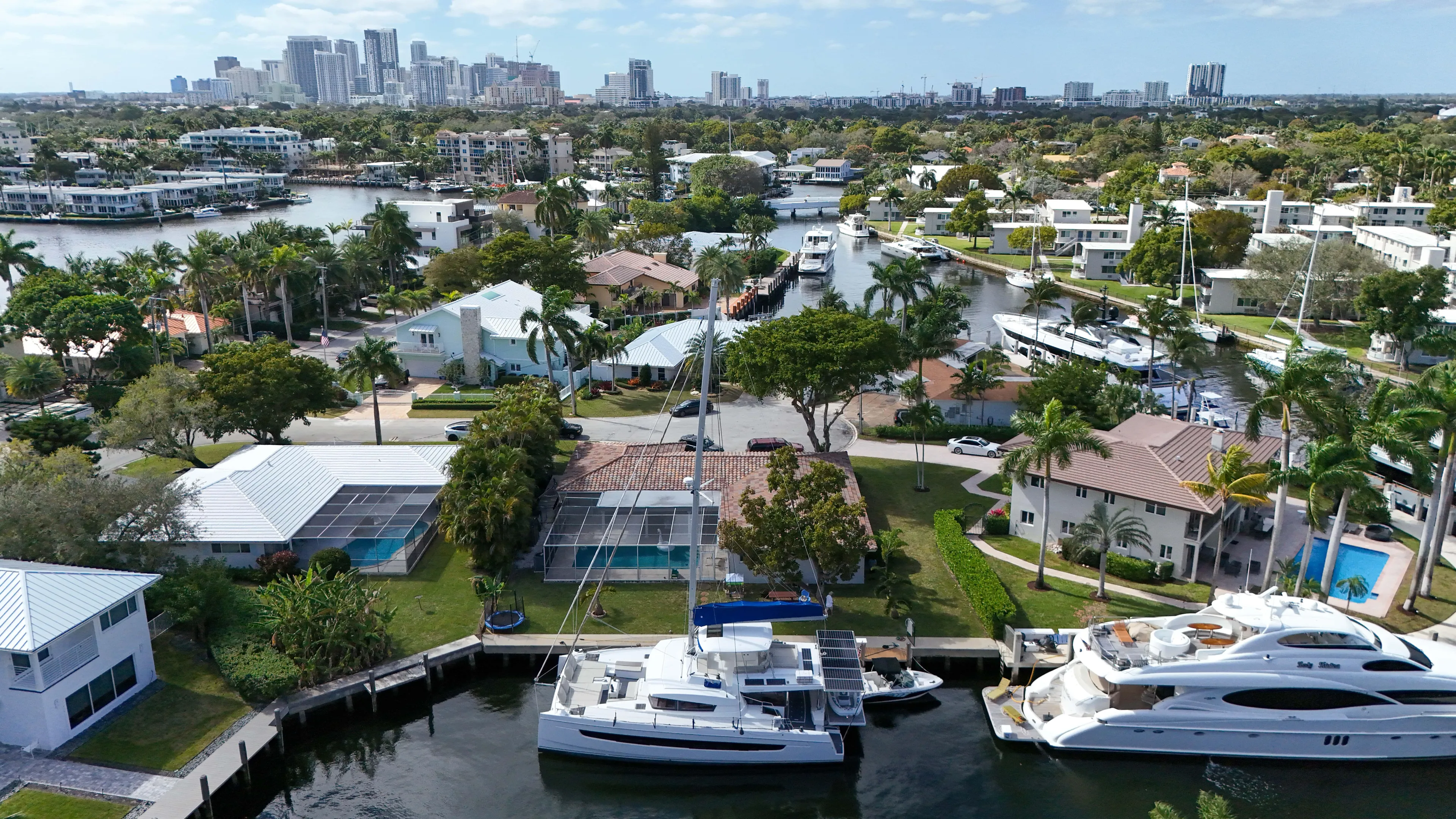Joy Yacht Photos Pics Aerial view of luxury yachts and waterfront homes in a tropical cityscape, featuring a Bali 5.4 catamaran.
