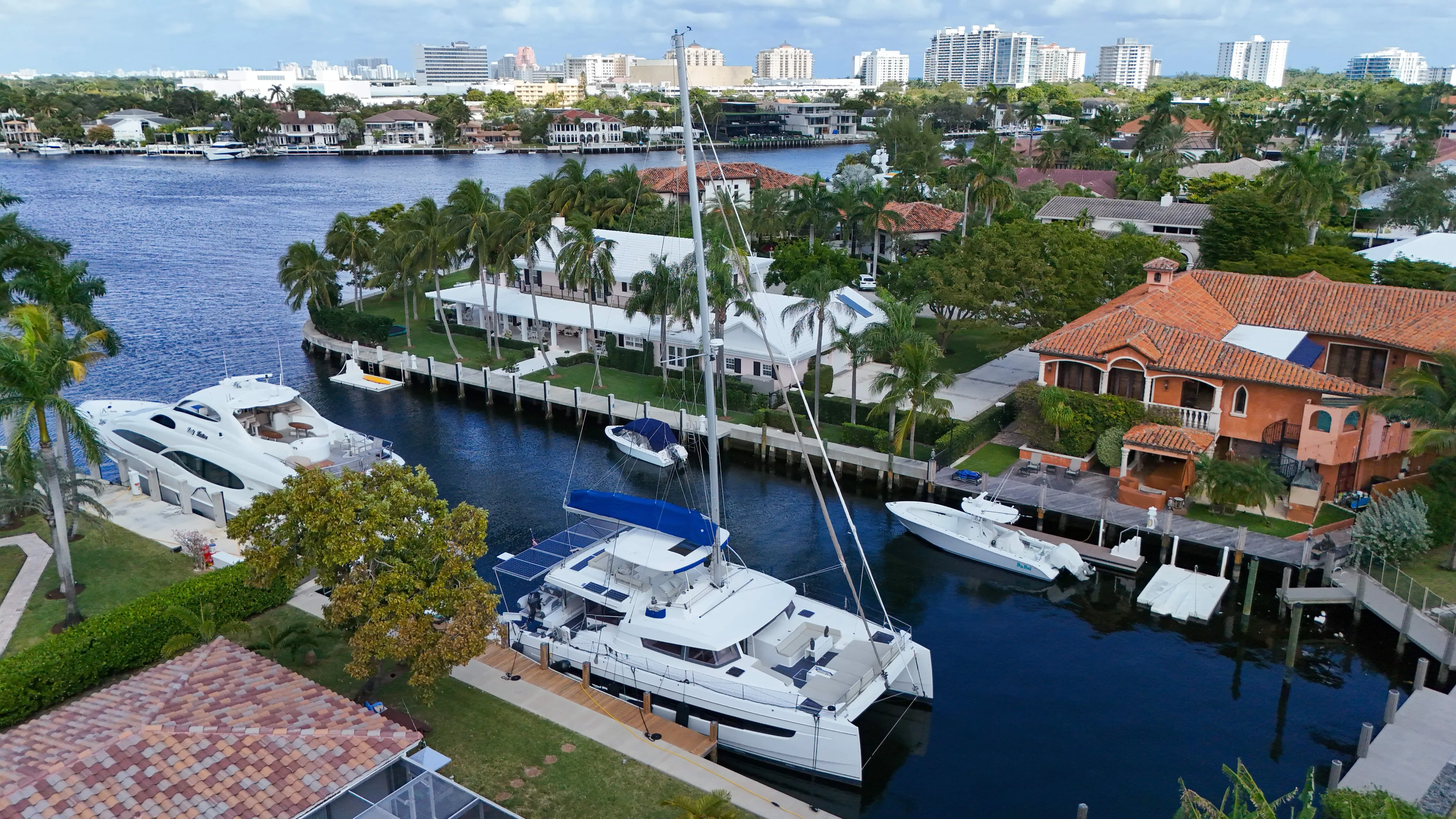 Joy Yacht Photos Pics Aerial view of Bali 5.4 catamaran docked in a scenic waterfront neighborhood.