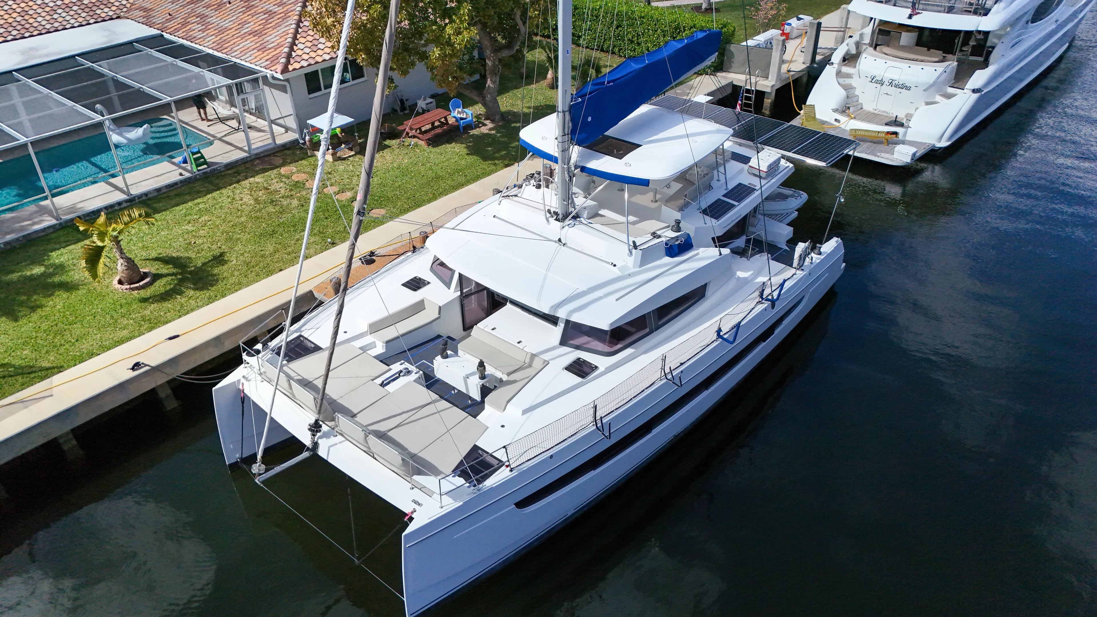 Joy Yacht Photos Pics Aerial view of a 2021 Bali 5.4 catamaran docked near a house with a pool.