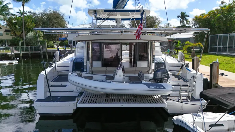 Joy Yacht Photos Pics Luxury Bali 5.4 catamaran docked, featuring spacious deck and tender boat, 2021 model.