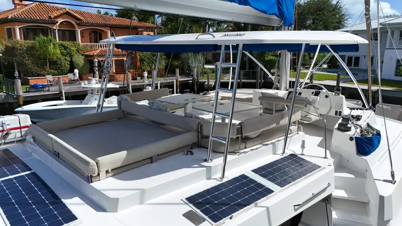 Joy Yacht Photos Pics 2021 Bali 5.4 catamaran with solar panels, docked near luxury waterfront homes.