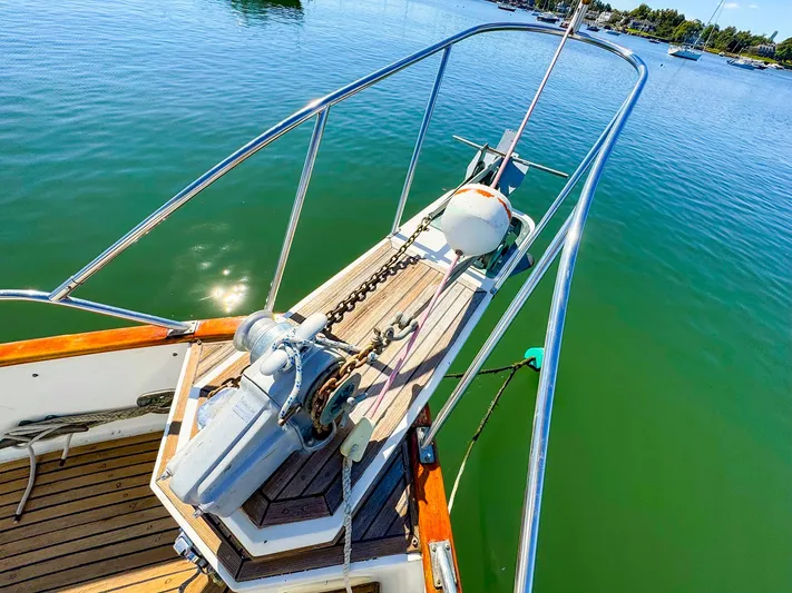 4796tw Yacht Photos Pics Grand Banks 42 Classic 1988 yacht bow with anchor, on calm green water.