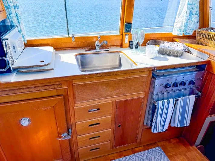 4796tw Yacht Photos Pics Galley kitchen in 1988 Grand Banks 42 Classic yacht with sink, stove, and wooden cabinetry.