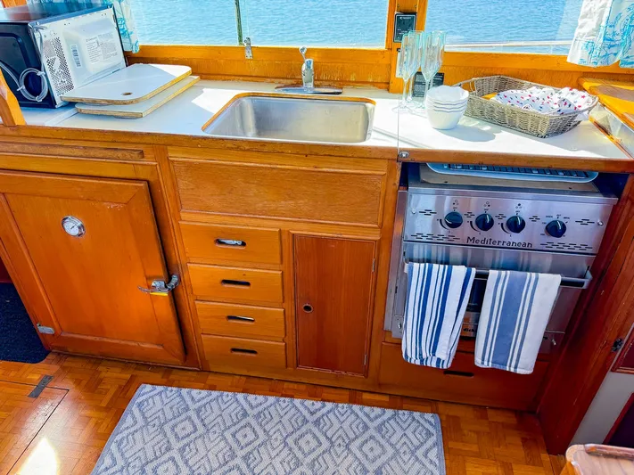 4796tw Yacht Photos Pics Galley kitchen in 1988 Grand Banks 42 Classic yacht with wood cabinetry and stainless steel sink.