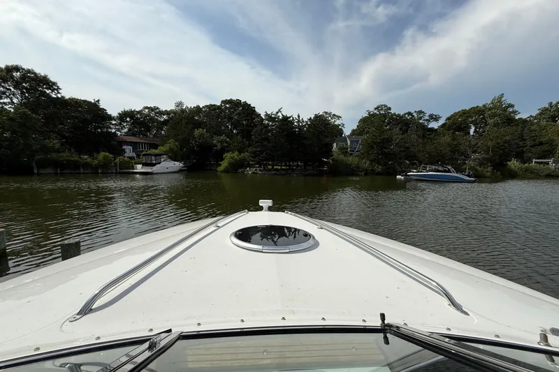  Yacht Photos Pics Bow view of 2013 Cobalt 323 boat on a serene lake with surrounding trees.