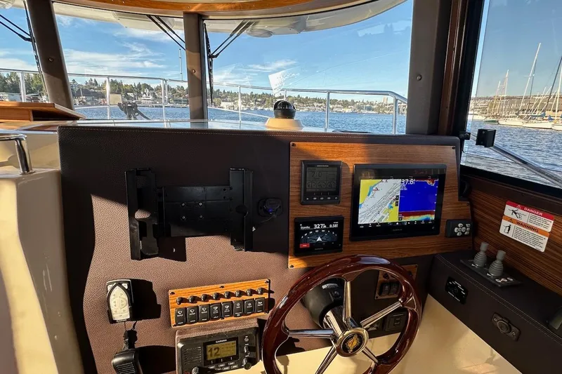 Buoy Boys Yacht Photos Pics 2025 Ranger Tugs R-29 CB helm with navigation screens and steering wheel, overlooking marina.