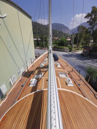  Yacht Photos Pics 2004 Hallberg-Rassy 62 yacht deck with wooden finish, docked near mountains.