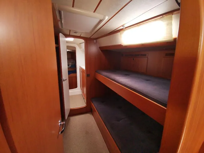  Yacht Photos Pics Interior of 2004 Hallberg-Rassy 62 yacht with wooden bunk beds and soft lighting.