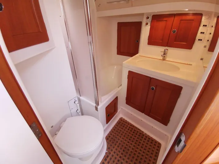  Yacht Photos Pics Bathroom interior of 2004 Hallberg-Rassy 62 yacht with wooden cabinets and white fixtures.