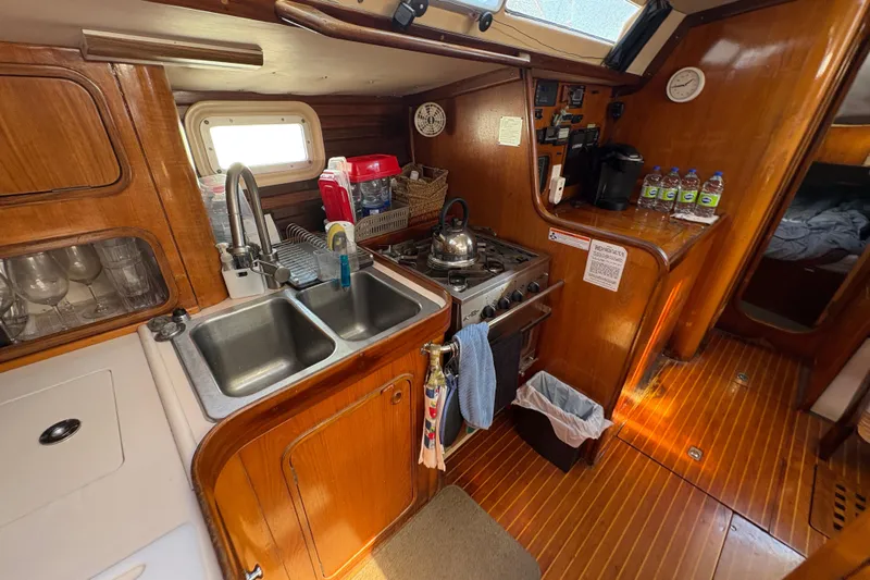 Skye Yacht Photos Pics Cozy kitchen in 1990 Beneteau Oceanis 500 sailboat with wooden cabinetry and dual sink.