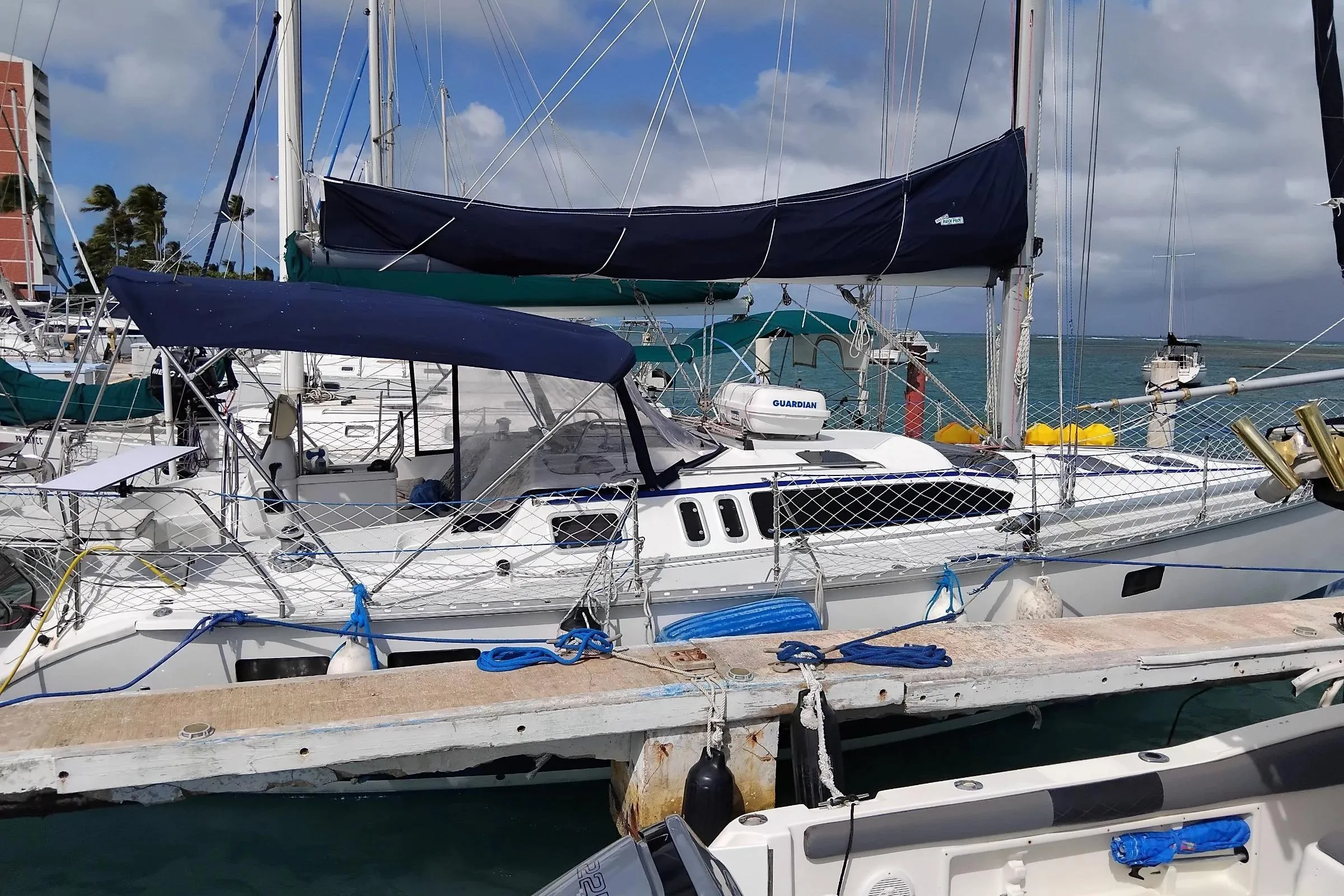 1994 Hunter Legend 40.5 sailboat docked at marina, featuring blue canopy and netting.
