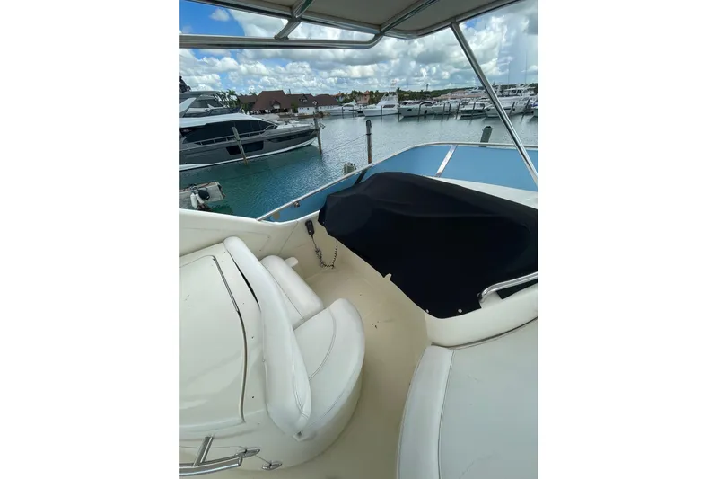  Yacht Photos Pics 2005 Azimut 55 Flybridge yacht interior with marina view, featuring white seating and covered controls.