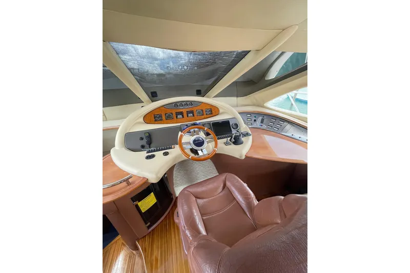  Yacht Photos Pics Helm of 2005 Azimut 55 Flybridge yacht with leather seat and wooden dashboard.