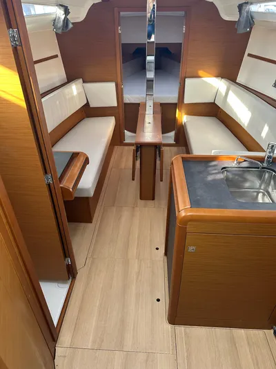  Yacht Photos Pics 2020 Jeanneau Sun Odyssey 349 interior with wood finish, seating, and compact kitchen area.