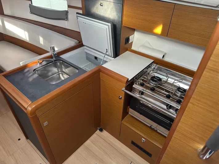  Yacht Photos Pics Modern kitchen in 2020 Jeanneau Sun Odyssey 349 yacht with sink, stove, and seating area.