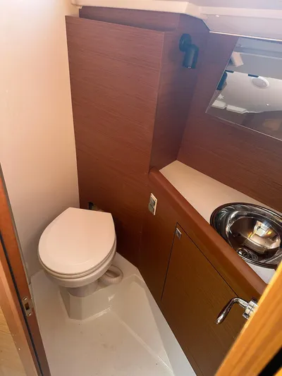  Yacht Photos Pics 2020 Jeanneau Sun Odyssey 349 yacht bathroom with toilet, sink, and wooden cabinetry.