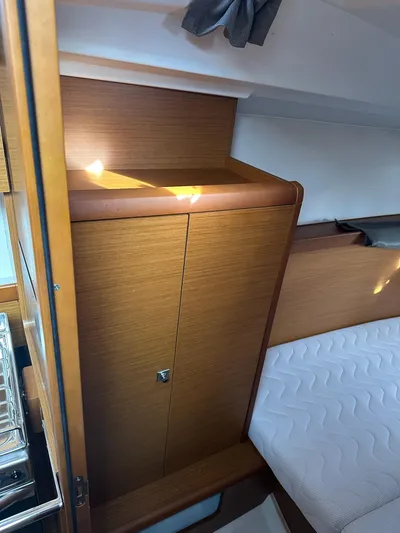  Yacht Photos Pics Interior of 2020 Jeanneau Sun Odyssey 349, featuring wooden cabinetry and a cozy bed.