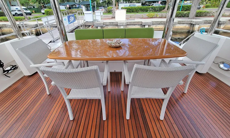 Suertudo Yacht Photos Pics Outdoor dining area on 2020 Outer Reef Yachts 720 Motoryacht with wicker chairs and wooden table.