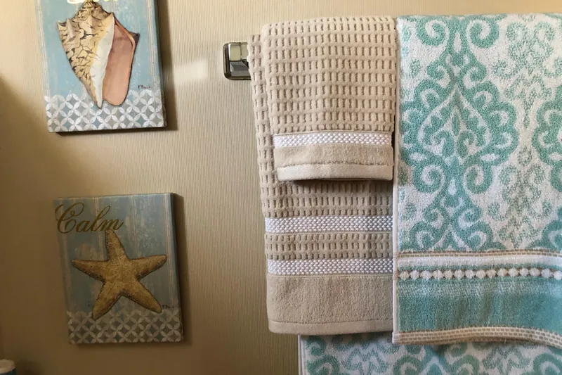  Yacht Photos Pics Nautical-themed bathroom decor with towels and seashell artwork on a 1988 Tollycraft yacht.