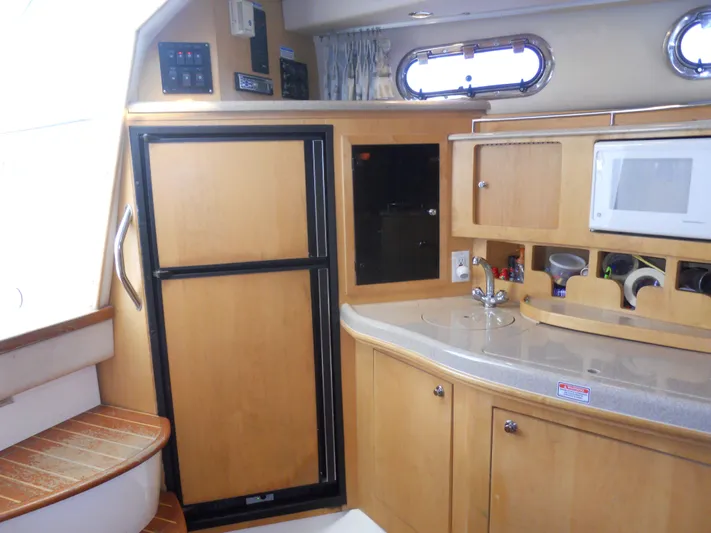 Fish Tales Yacht Photos Pics Interior of 2000 Boston Whaler 34 Defiance, featuring kitchenette with cabinets and appliances.